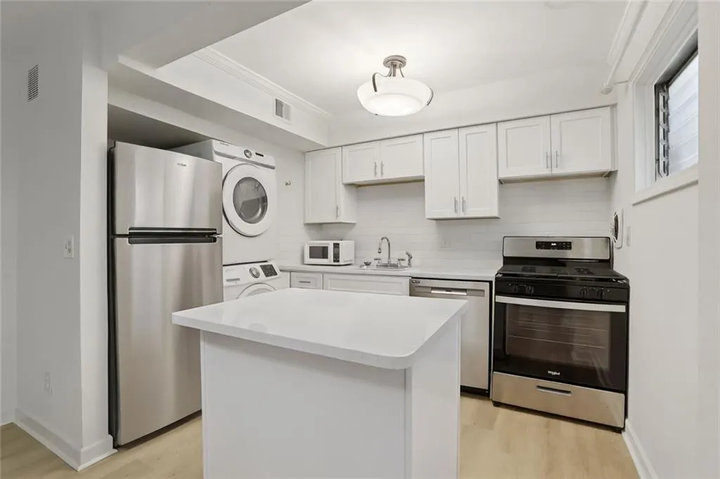Kitchen featuring white cabinetry, appliances with stainless steel finishes, light wood-type flooring, and decorative backsplash
