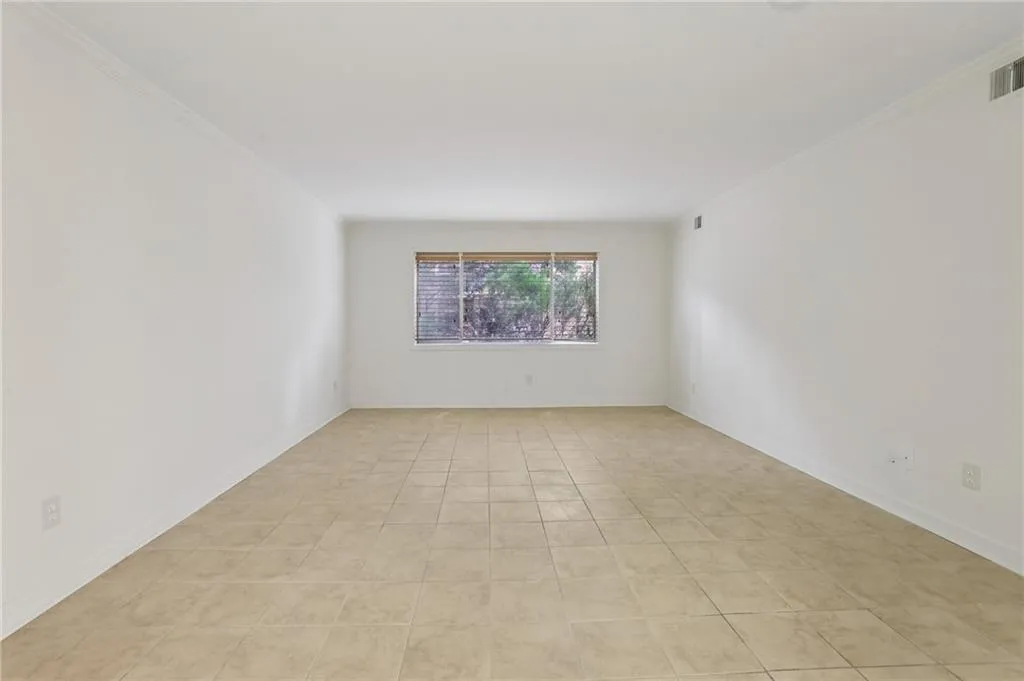 Empty room with crown molding and light tile patterned floors