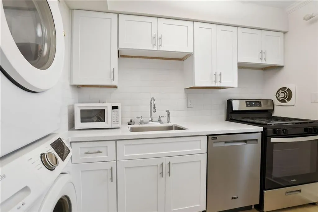 Kitchen featuring appliances with stainless steel finishes, white cabinetry, and tasteful backsplash