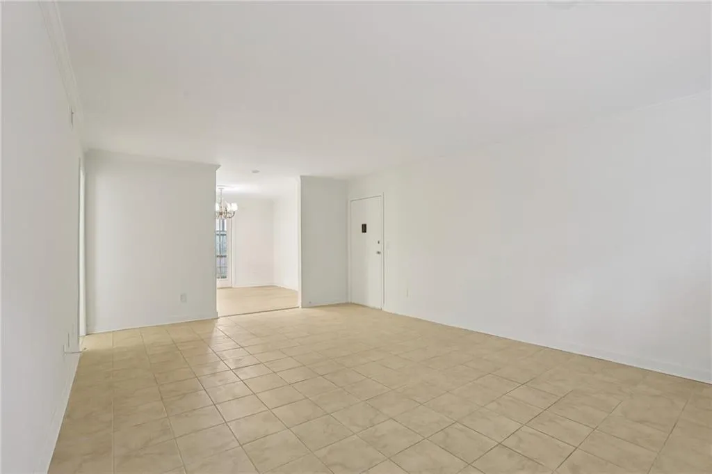 Empty room featuring a chandelier, light tile patterned floors, and crown molding