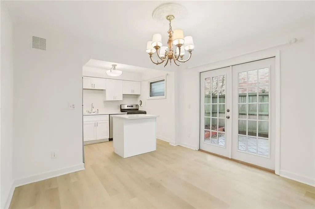 Kitchen with white cabinetry, pendant lighting, a center island, light countertops, and light wood finished floors