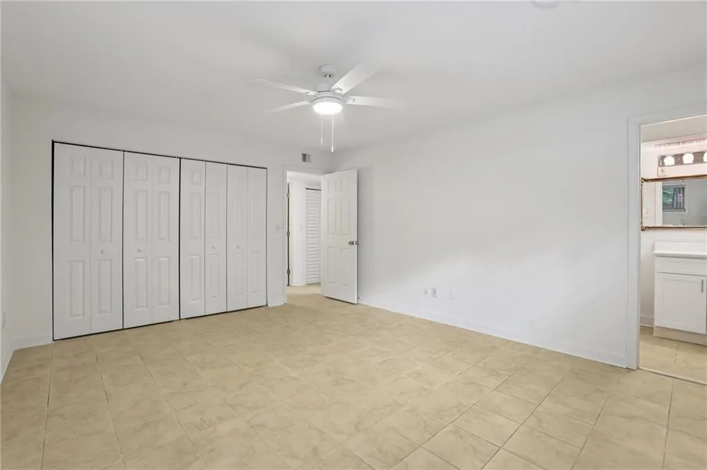 Unfurnished bedroom featuring a closet, a ceiling fan, light tile patterned flooring, and connected bathroom