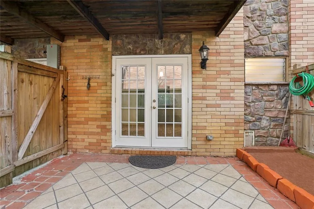 Property entrance with a patio, brick siding, and french doors