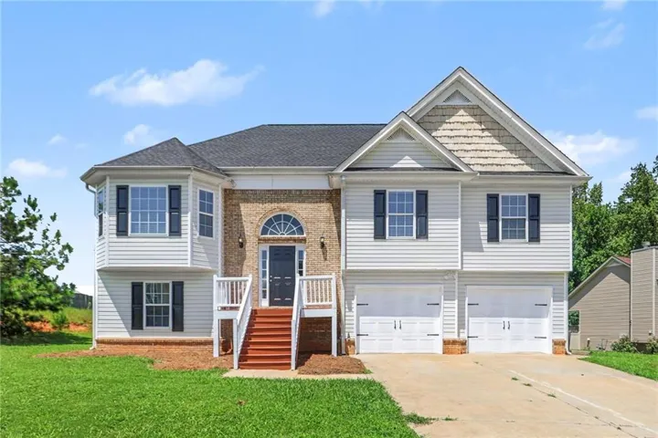 Two-story residence featuring a brick facade, white siding, bay window, and a two-car garage