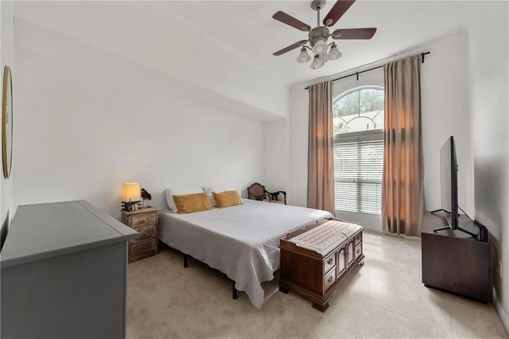 Bedroom featuring light carpet, ornamental molding, and a ceiling fan