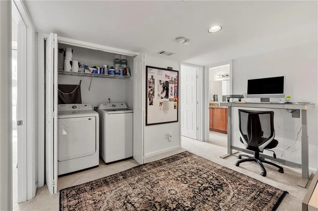 Washroom featuring light colored carpet, an office area, and separate washer and dryer