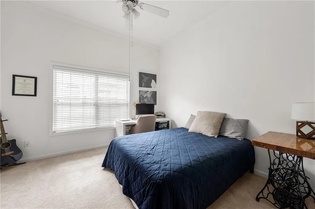 Carpeted bedroom with ornamental molding and ceiling fan