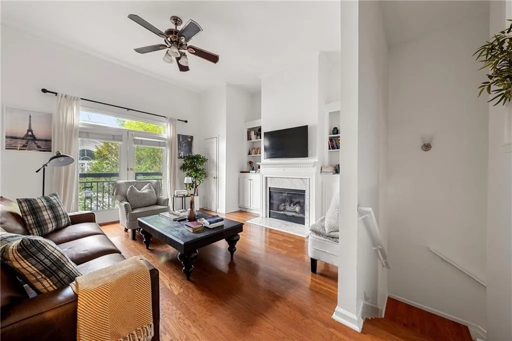 Living area featuring light wood-flooring, a fireplace, a ceiling fan, and built in features