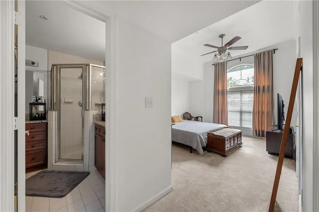 Bedroom featuring light colored carpet, a ceiling fan, and light tile patterned flooring