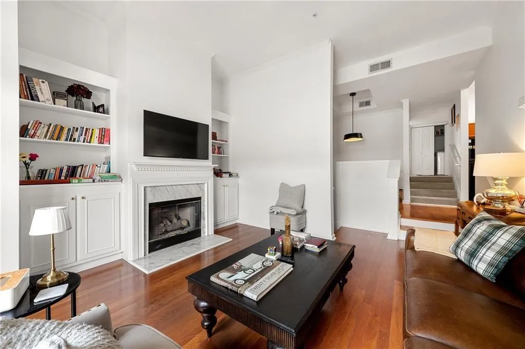 Living area with stairway, dark wood finished floors, a premium fireplace, built in shelves, and crown molding