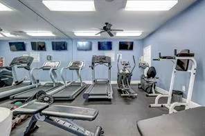 Gym with baseboards and ceiling fan