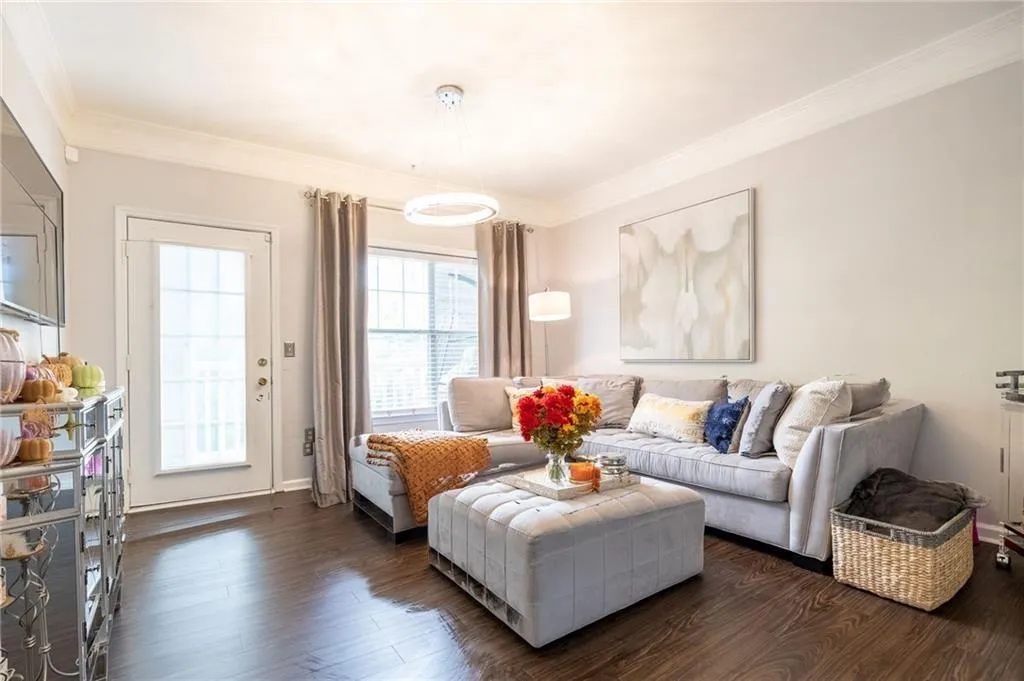 Living area with crown molding and dark wood-type flooring