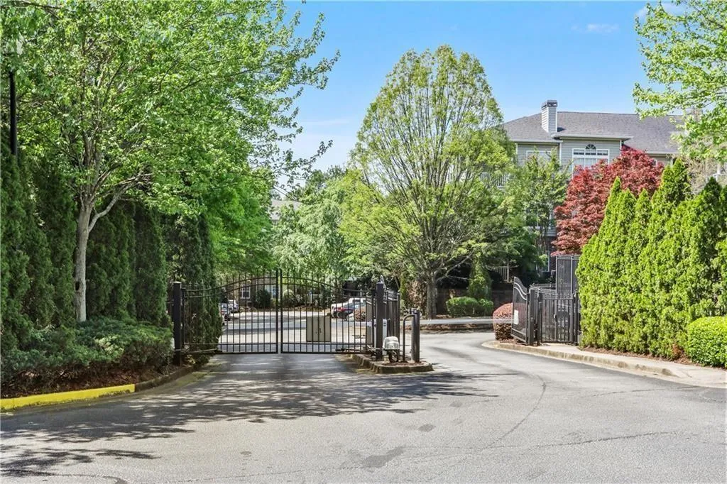 View of asphalt road featuring a gate, curbs, and a gated entry