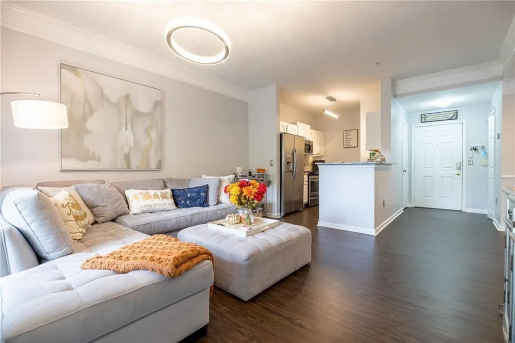 Living room featuring dark wood-style flooring, ornamental molding, and baseboards