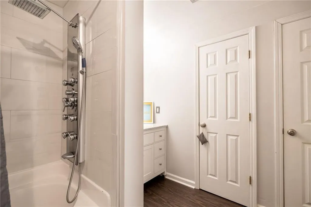 Full bath with a shower, wood finished floors, vanity, baseboards, and a tub to relax in