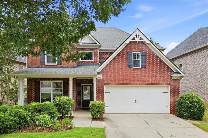 Charming two-story brick residence featuring a welcoming front elevation with gabled roofline, white trim accents, and a two-car garage