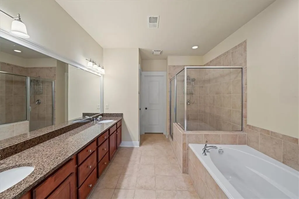 Bathroom featuring double vanity, a bath, a shower stall, light tile patterned floors, and recessed lighting