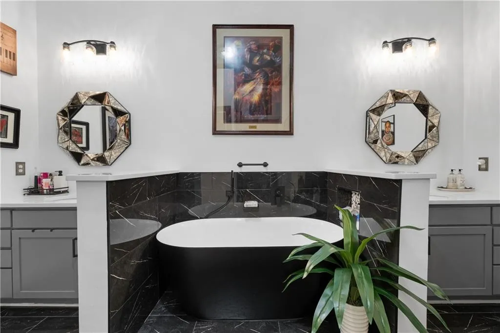 Bathroom featuring vanity, marble look tile flooring, a freestanding tub, and tile walls