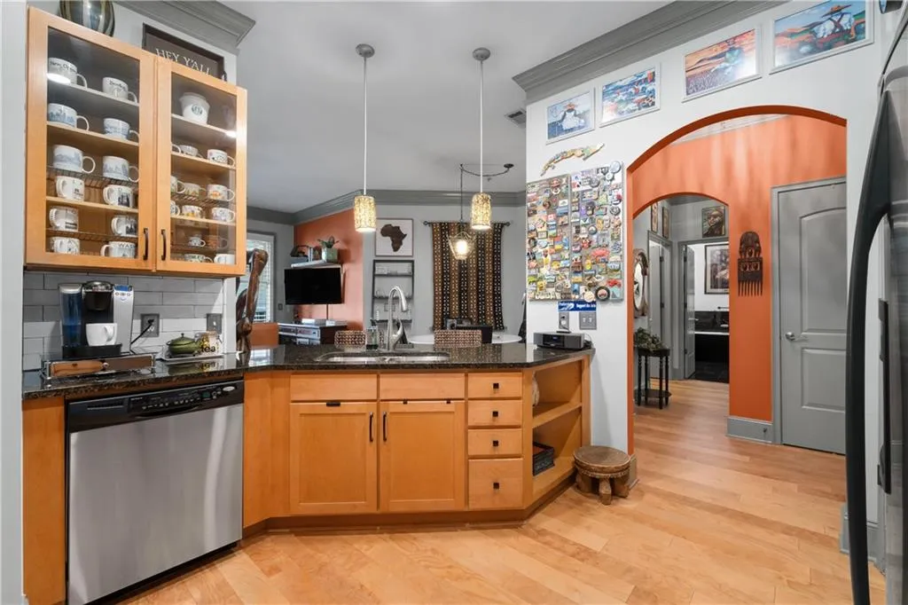 Kitchen featuring dishwasher, arched walkways, hanging light fixtures, decorative backsplash, and light wood-style flooring
