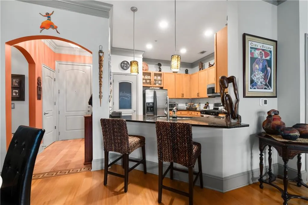 Kitchen with a peninsula, ornamental molding, backsplash, light wood-style flooring, and arched walkways