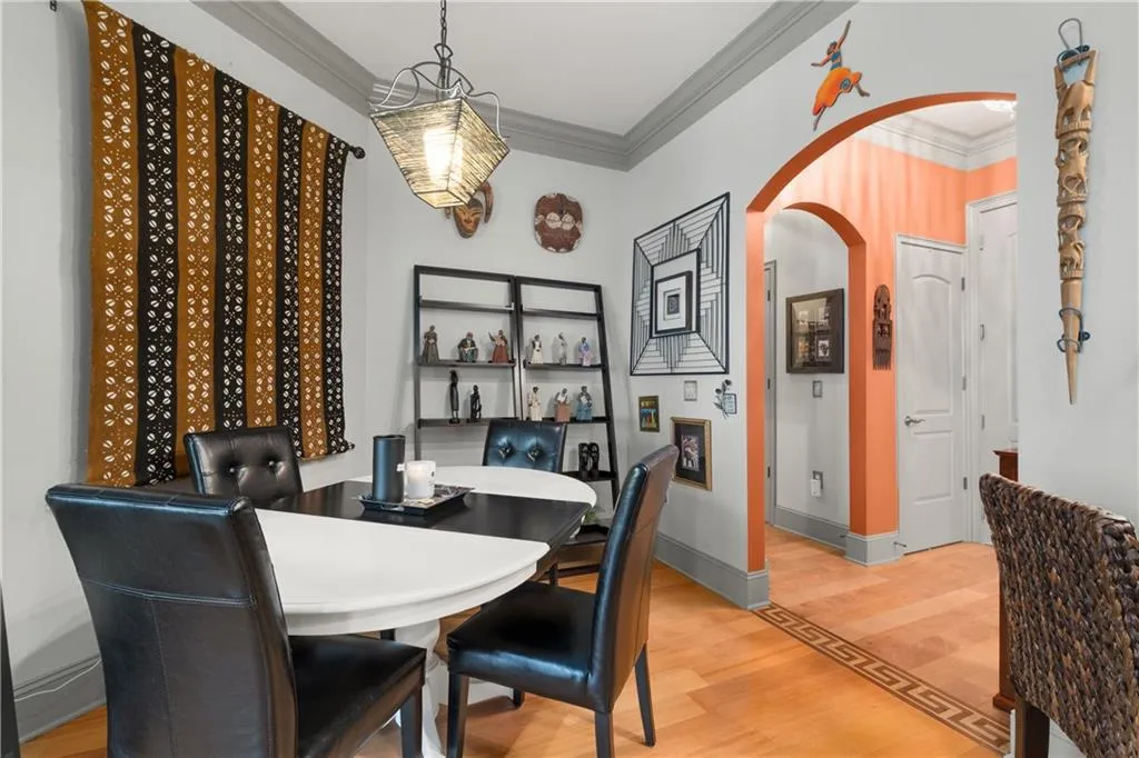 Dining area with arched walkways, crown molding, and light wood-style floors