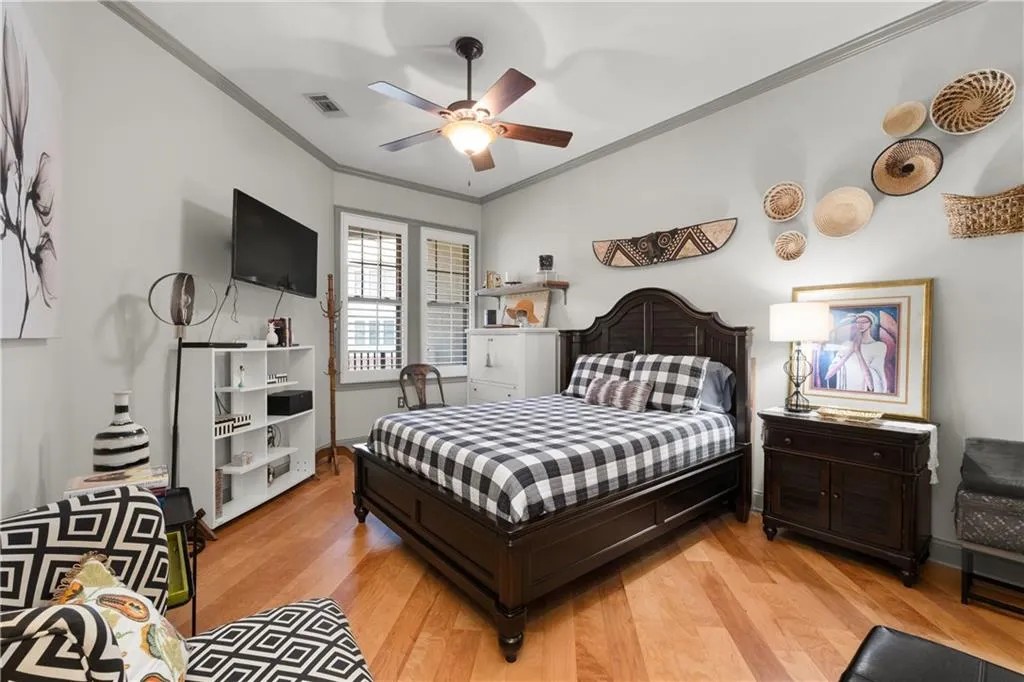 Bedroom with crown molding, light wood-style floors, and a ceiling fan