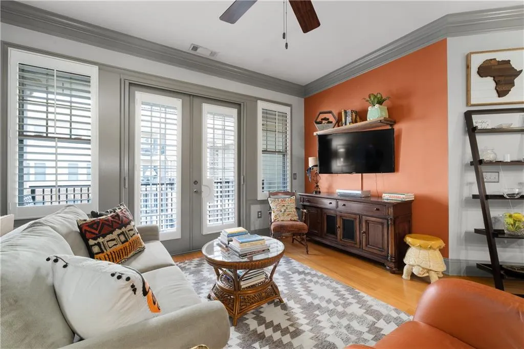 Living room featuring french doors, crown molding, light wood-style floors, and a ceiling fan