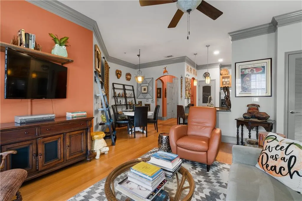 Living room with arched walkways, a ceiling fan, ornamental molding, and wood finished floors