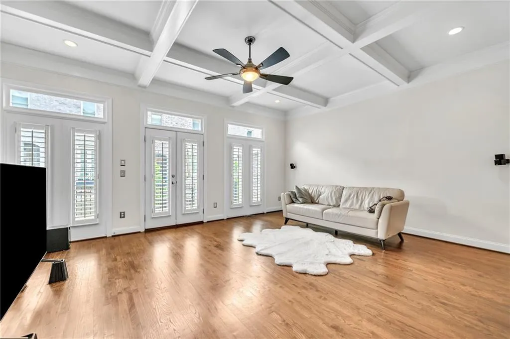 Living area with light wood finished floors, beam ceiling, recessed lighting, coffered ceiling, and ceiling fan