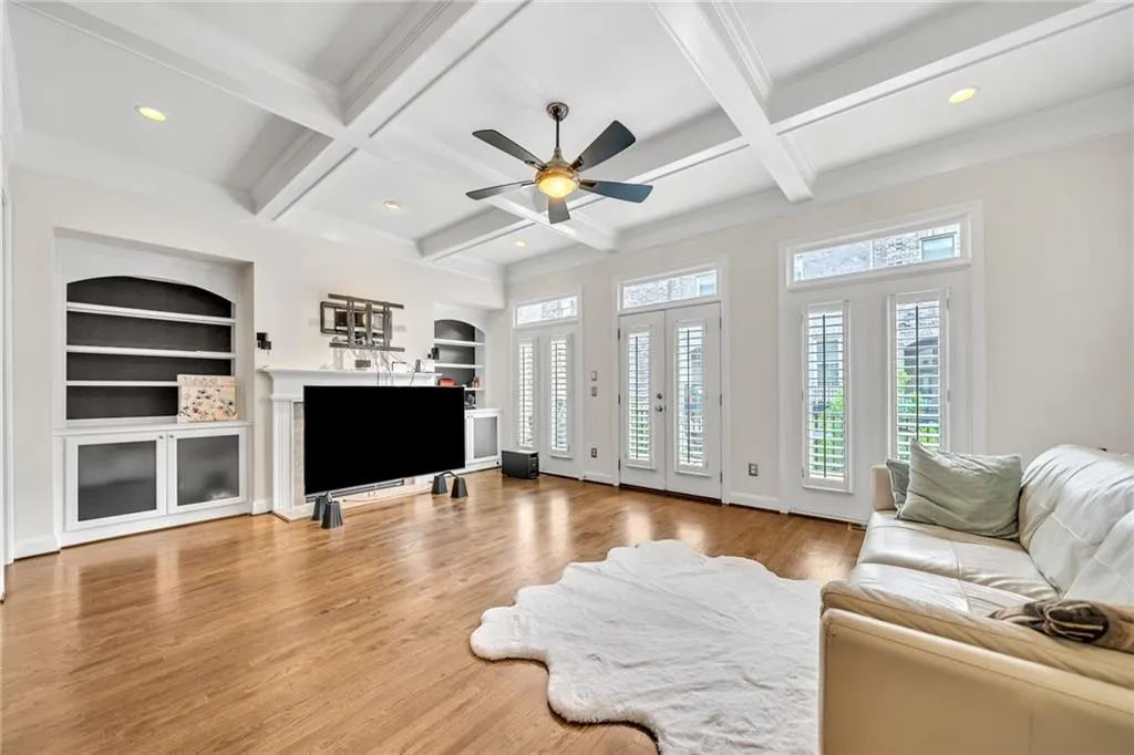 Living area featuring built in shelves, light wood-style flooring, beam ceiling, recessed lighting, and coffered ceiling