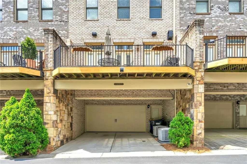 Back of property with brick siding, a balcony, and a garage