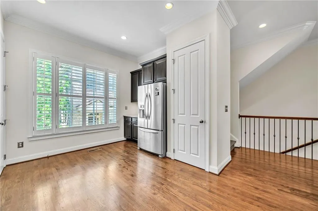 Kitchen featuring stainless steel refrigerator with ice dispenser, crown molding, light countertops, light wood-type flooring, and recessed lighting