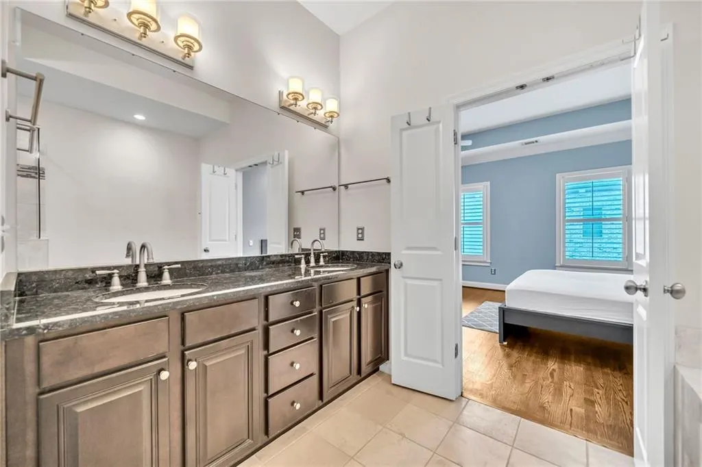 Ensuite bathroom with double vanity and light tile patterned flooring