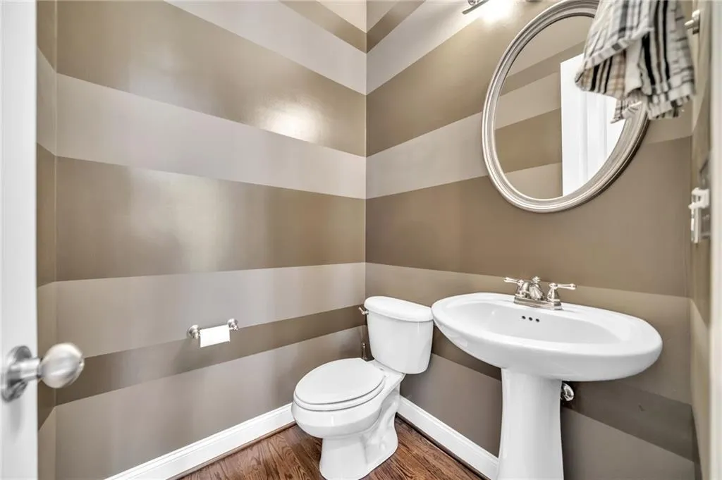 Half bathroom featuring toilet and wood finished floors