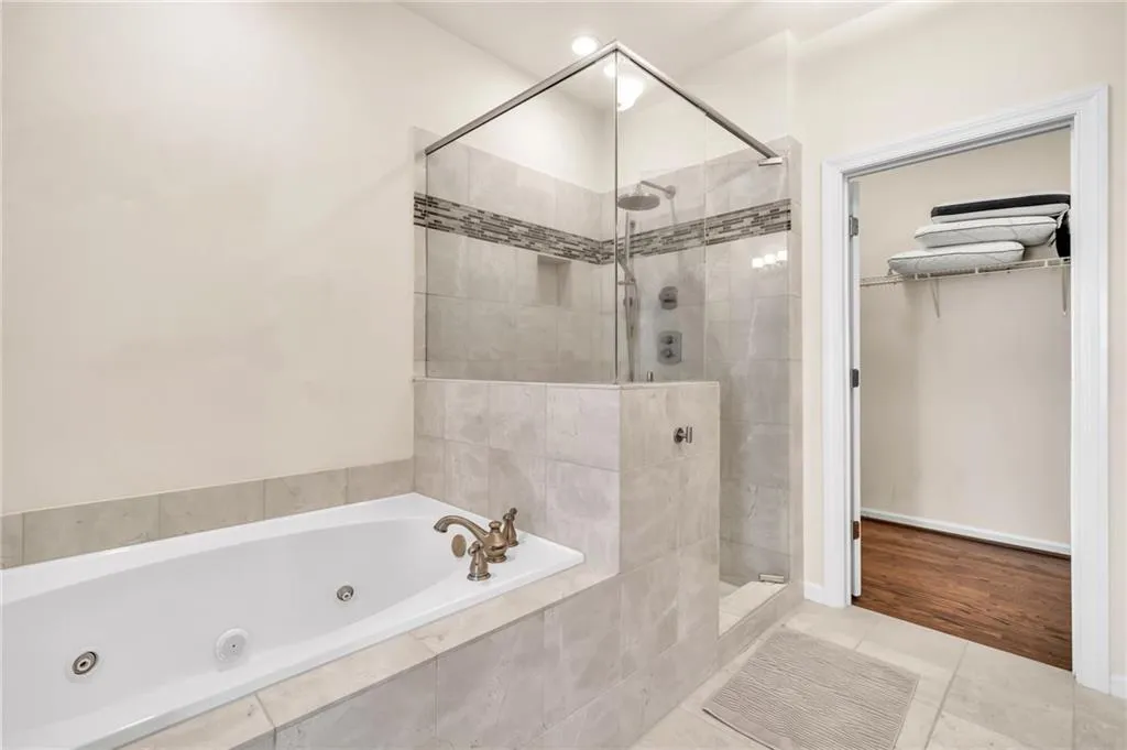 Full bathroom with a jetted tub, walk in shower, tile patterned flooring, and a walk in closet