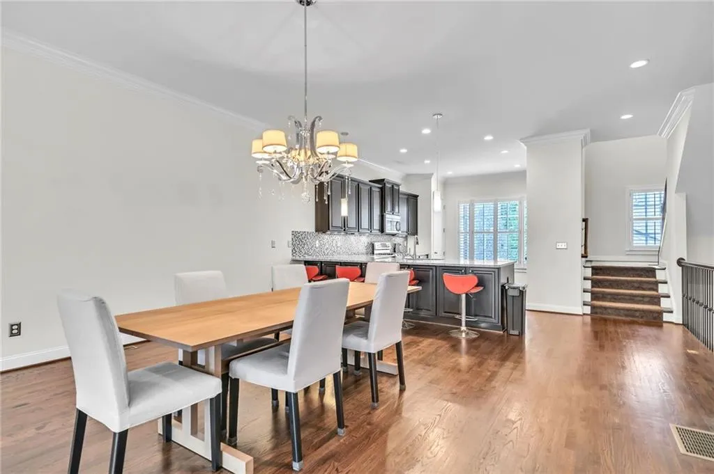 Dining space featuring crown molding, dark wood-style flooring, stairway, recessed lighting, and a chandelier