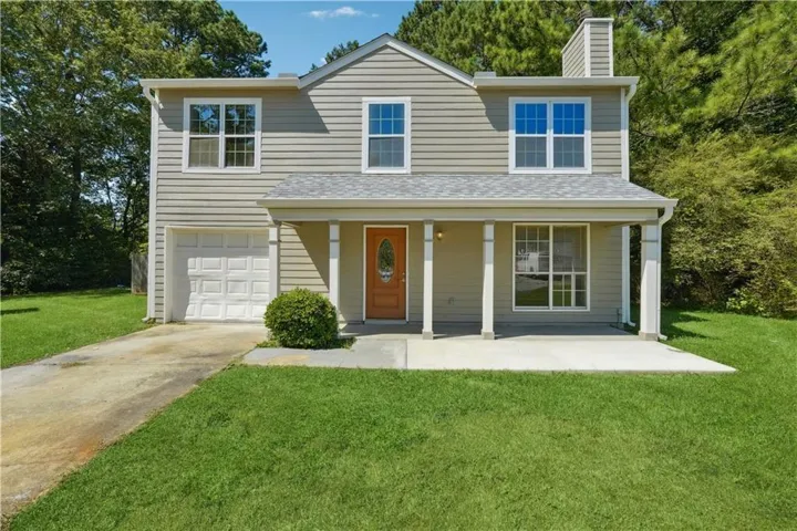 Two-story residence featuring light-colored siding, an attached single-car garage, and a covered front porch with white columns
