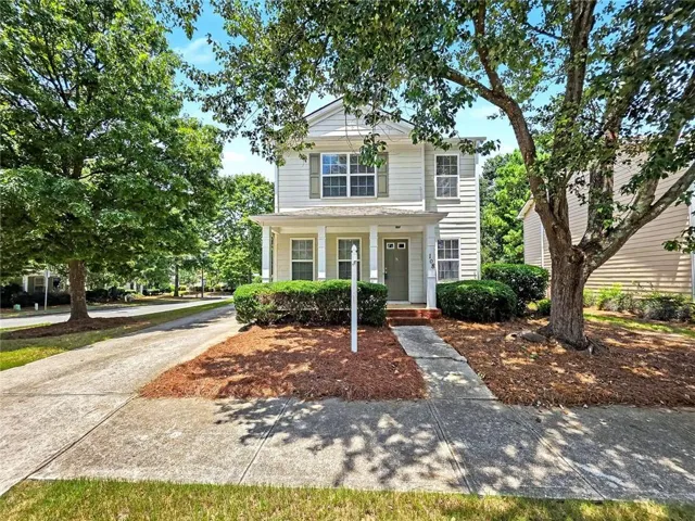 Two-story residence featuring light-colored siding, contrasting shutters, and a covered front porch with white columns