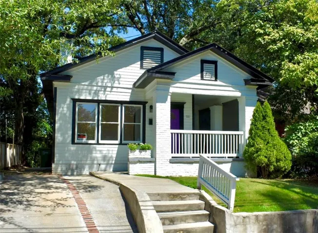 White siding exterior with black trim accents and a covered front porch featuring white railings