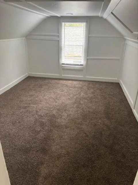 Bonus room featuring lofted ceiling, carpet, and a decorative wall