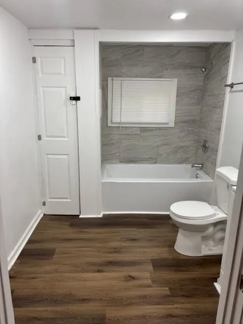 Full bath with wood finished floors, recessed lighting, and washtub / shower combination