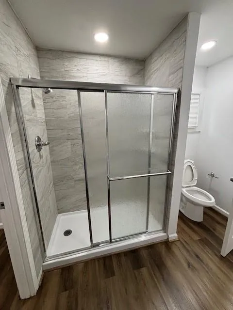 Bathroom featuring a shower stall, wood finished floors, and recessed lighting