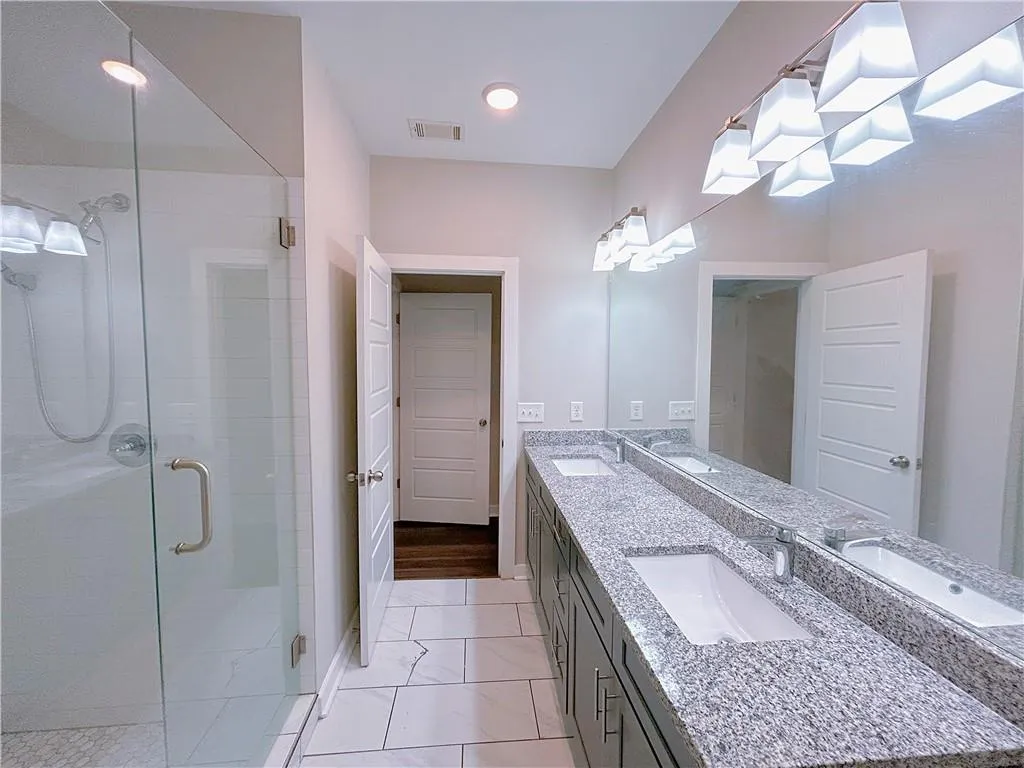 Bathroom with vanity, wood-type flooring, and a shower with door