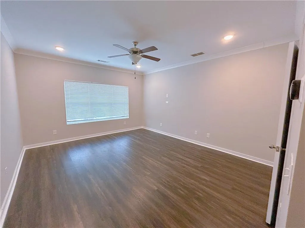 Unfurnished room with dark hardwood / wood-style floors, ceiling fan, and ornamental molding