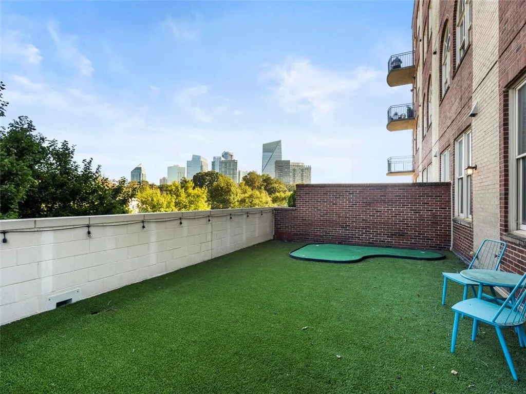 Rooftop patio featuring artificial turf, a putting green, and brick wall accents