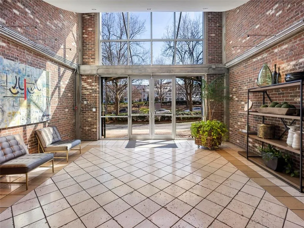 High ceilings with exposed brick walls, expansive window-wall, glass entry doors, and tiled flooring