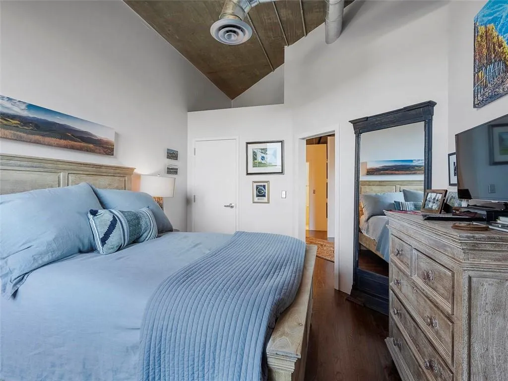 Vaulted ceiling with wood-finish paneling, exposed ductwork, wood-finish flooring, and solid core doors