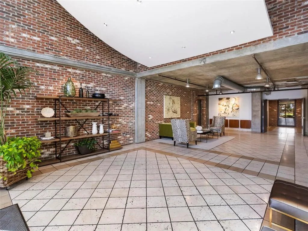 Exposed brick walls, tile flooring with decorative inlay, concrete ceilings, exposed ductwork, and track lighting fixtures