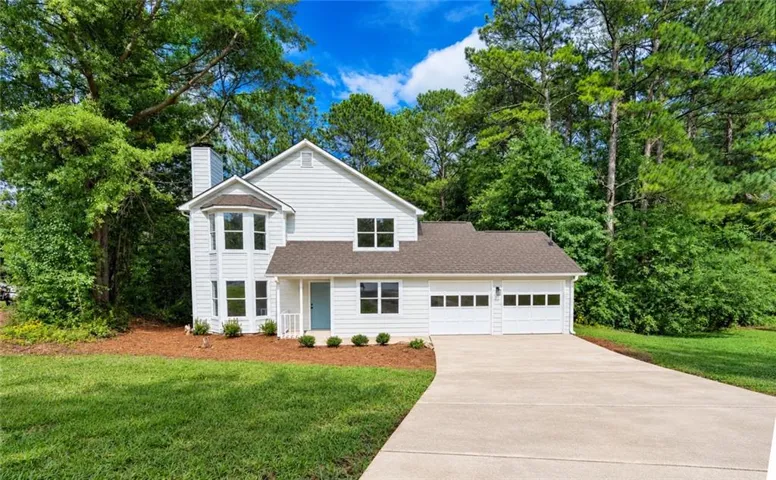 Modern white siding home with a two-car garage, bay windows, and a paved driveway