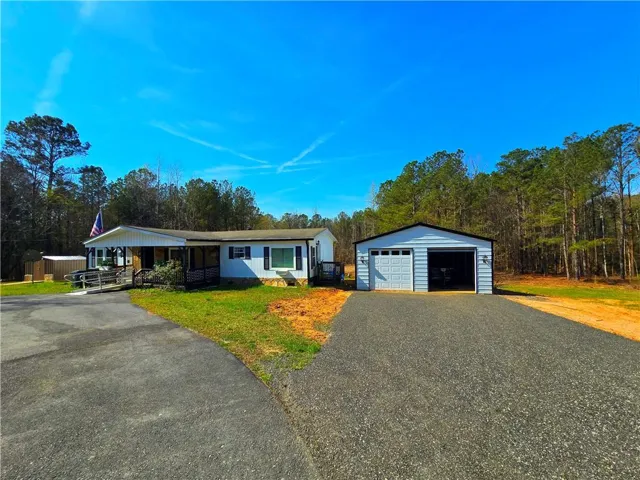 Property exterior featuring a covered front porch with ramp access, white siding, and dark shutters